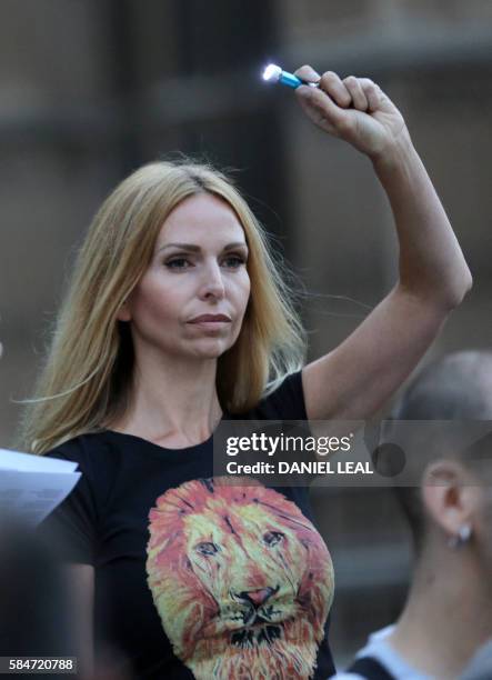 Woman waves a torch at a vigil in remembrance of lions killed by trophy hunters in central London on July 30, 2016. - Cecil was killed by American...