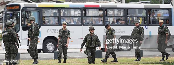 Soldiers keep watch in front of a bus before an event inaugurating a new subway line July 30, 2016 in Rio de Janeiro, Brazil. After many delays, the...