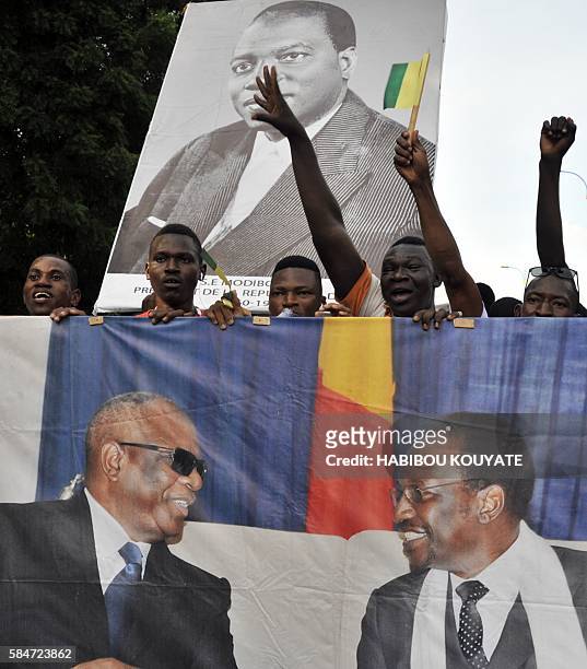 Protestors hold a banner picturing Mali's President Ibrahim Boubacar Keita and former Mali's President Dioncounda Traore and a portrait of Modibo...