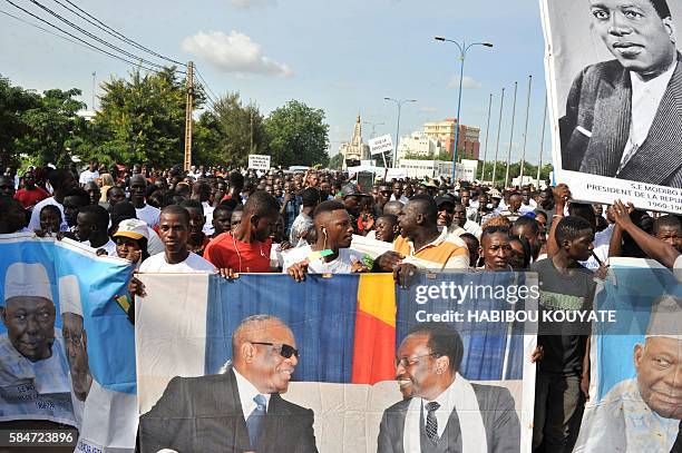 Protestors hold a banner picturing Mali's President Ibrahim Boubacar Keita and former Mali's President Dioncounda Traore and a portrait of Modibo...