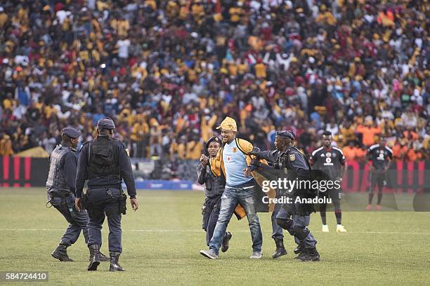 Police officer cathces a fan of Kaiser Chiefs during 2016 Carling Black Label Cup between Kaizer Chiefs F.C. And Orlando Pirates at FNB Stadium in...