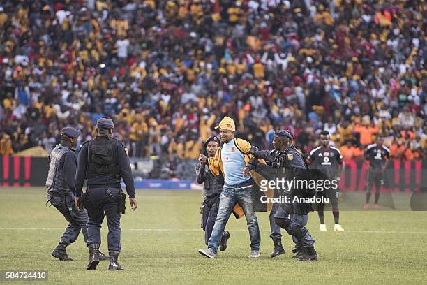 Police officer cathces a fan of Kaiser Chiefs during 2016 Carling Black Label Cup between Kaizer Chiefs F.C. And Orlando Pirates at FNB Stadium in...