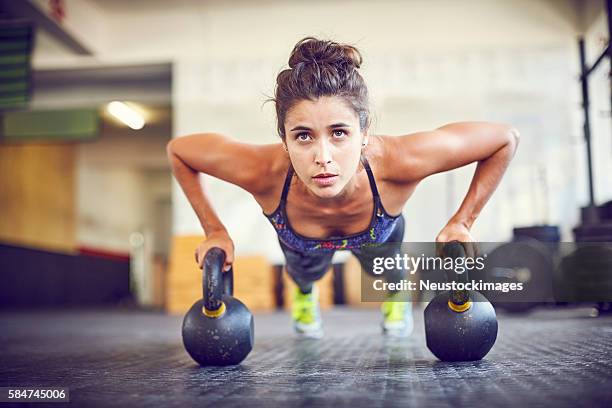 atleta enfocado haciendo flexiones en kettlebells en el gimnasio - flexiones fotografías e imágenes de stock