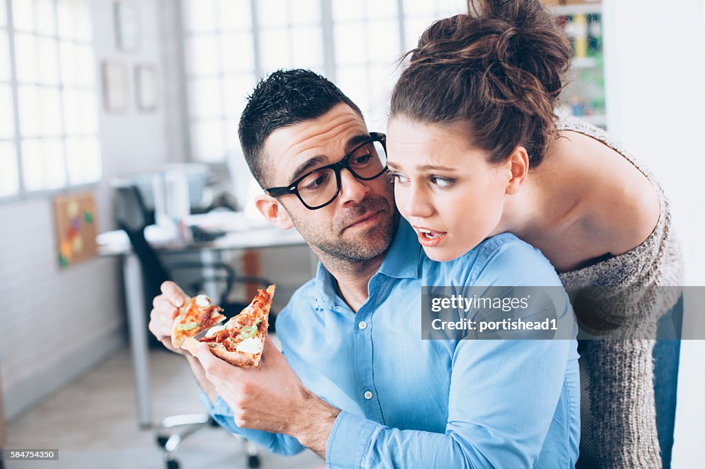 Young couple having pizza lunch break at workplace