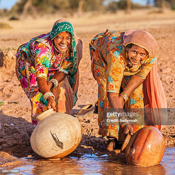 indian women collecting water from the lake, rajasthan - village life stockfoto's en -beelden