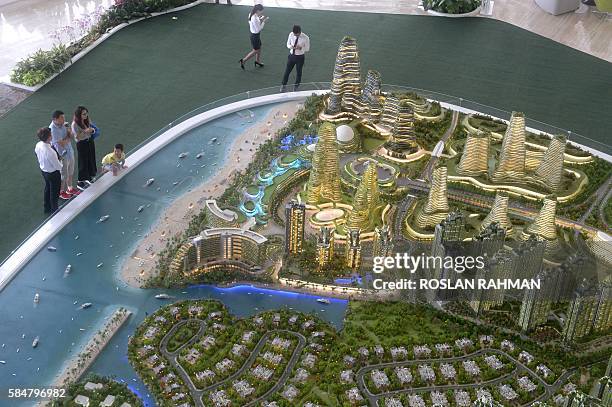 This picture taken on April 19, 2016 shows visitors view the scale model of development at Forest-City on one of the man-made islands on the...