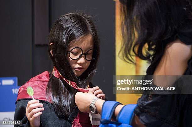 Mother dresses her daughter up as a Harry Potter character before taking photos in front of a poster advertising the new book 'Harry Potter and the...