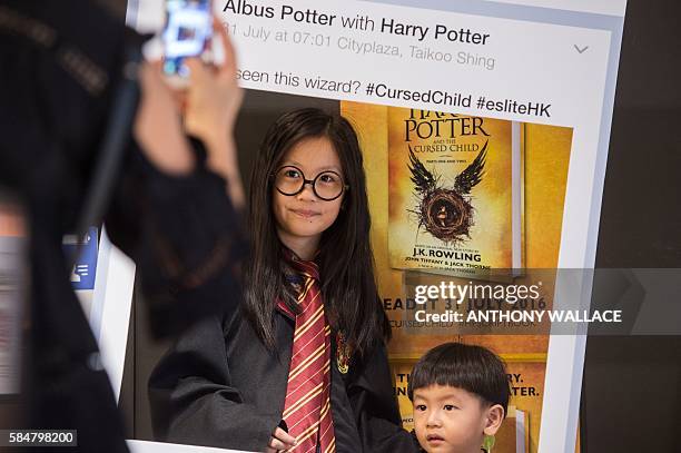 Mother takes photos of her children dressed up as Harry Potter characters in front of a poster advertising new book 'Harry Potter and the Cursed...
