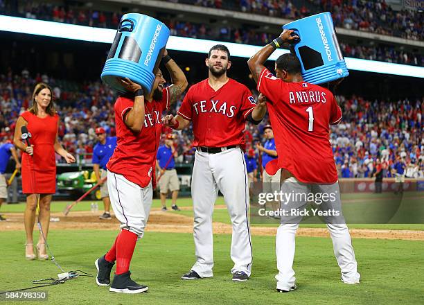 Elvis Andrus of the Texas Rangers and Rougned Odor circle Mitch Moreland with the coolers after Moreland walk off home run against the Kansas City...