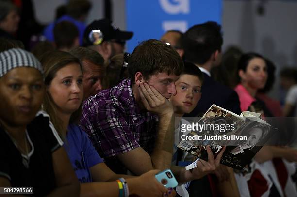 Supporter reads a book as he waits for the start of a campaign rally woth democratic presidential nominee former Secretary of State Hillary Clinton...