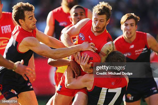 Ryan Davis of the Suns is tackled by Dom Tyson of the Demons and Sam Frost during the round 19 AFL match between the Melbourne Demons and the Gold...