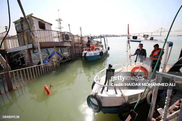 Members of Iraqi river police stand on their boat as they inspect a small casino boat that sank in the Shatt al-Arab river after a small device...