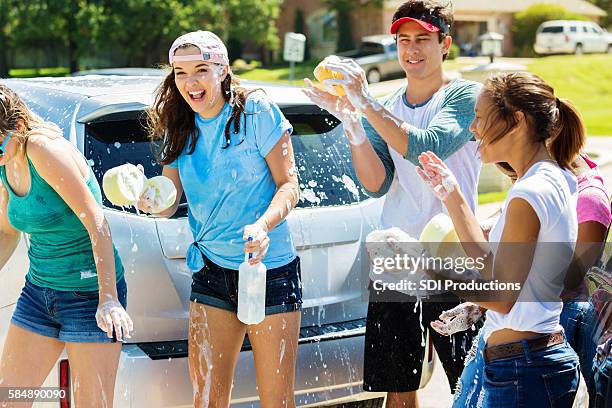 洗車場で遊んで飛び散る幸せな十代の若者たち - car wash ストックフォトと画像