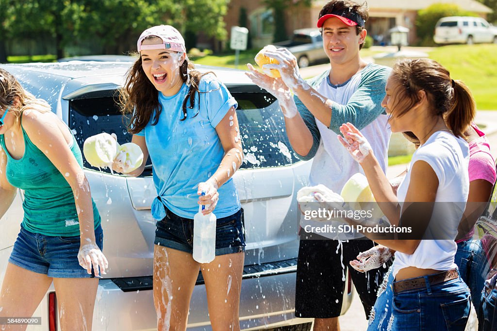 Happy teens playing and splashing around at a car wash