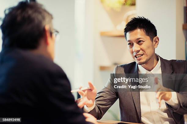 two men in a casual meeting in a cafe - japanese people stock pictures, royalty-free photos & images