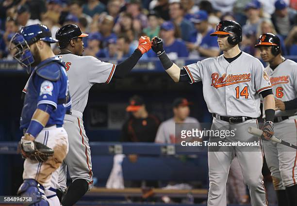 Adam Jones of the Baltimore Orioles is congratulated by Nolan Reimold and Jonathan Schoop after hitting a three-run home run in the twelfth inning...