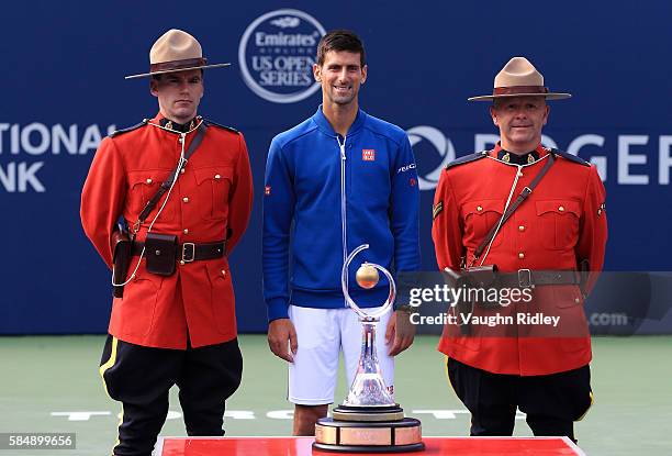 Novak Djokovic of Serbia celebrates with 2 Canadian Mounties after winning the Singles Final over Kei Nishikori of Japan during Day 7 of the Rogers...