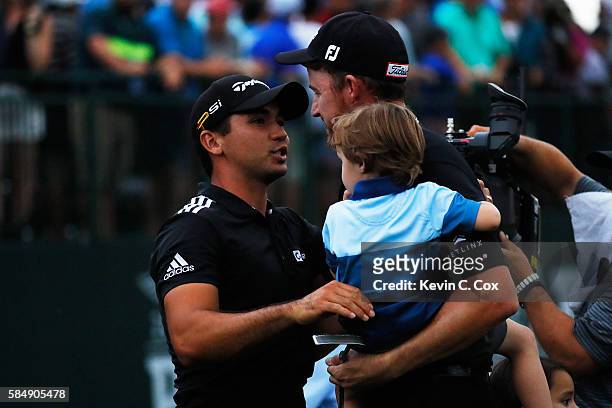 Jimmy Walker of the United States is congratulated on his victory by Jason Day of Australia while holding his son Beckett on the 18th green during...