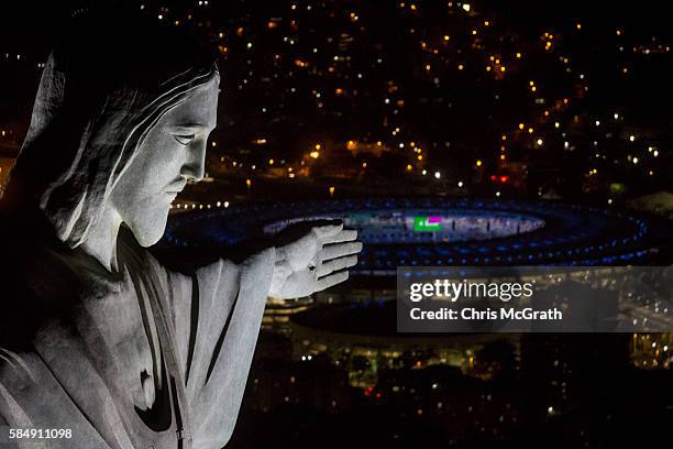 The Christ the Redeemer statue is seen at sunset in front of the Maracana Stadium ahead of the 2016 Summer Olympic Games on July 31, 2016 in Rio de...