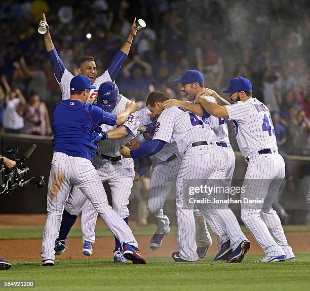 Players for the Chicago Cubs including Anthony Rizzo and Jake Arrieta mob Jon Lester after he bunted in the winning run against the Seattle Mariners...