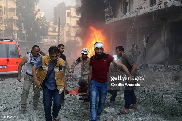 Civilians carry an attack victim after Assad forces hit residential areas in Ansari neighborhood of Aleppo, Syria on July 31, 2016. Several...