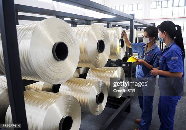 Chinese workers check carbon fiber silk thread at a carbon fiber factory in Lianyungang, in eastern China's Jiangsu province on August 1, 2016....