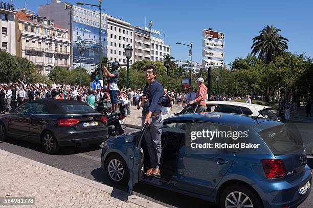 Portuguese drivers and riders, forced to stop their vehicles for the crowds, watch their national football team during their victory procession...