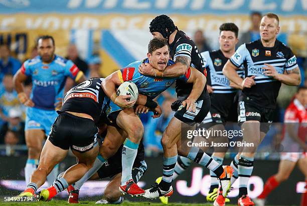 Greg Bird of the Titans is tackled by Michael Ennis of the Sharks during the round 21 NRL match between the Gold Coast Titans and the Cronulla Sharks...