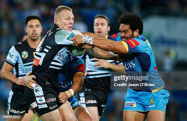 Luke Lewis of the Shark's takes on the Titans defence during the round 21 NRL match between the Gold Coast Titans and the Cronulla Sharks at Cbus...