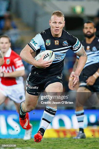 Luke Lewis of the Shark's takes on the Titans defence during the round 21 NRL match between the Gold Coast Titans and the Cronulla Sharks at Cbus...