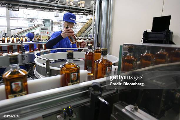Worker checks a bottle of Black Nikka Clear whisky on the production line at Nikka Whisky Distilling Co., Ltd. Factory in Kashiwa, Chiba Prefecture,...