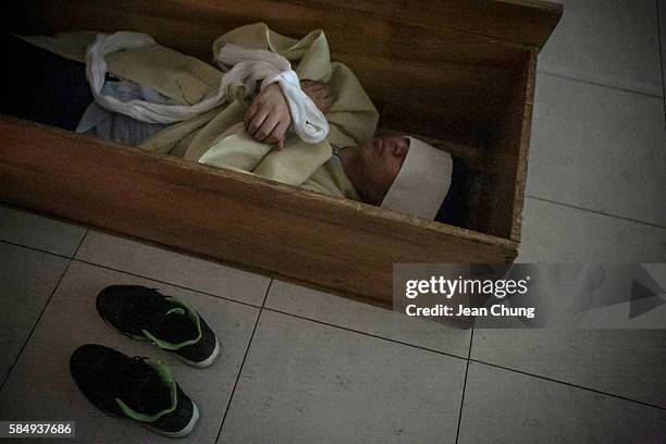 Participants wearing linen shrouds meditate and think about their life as they lie down in a coffin during a "Death Experience/Fake Funeral" session...