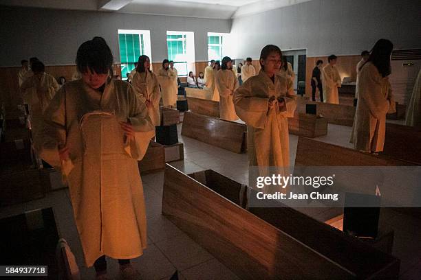 Participants wear the linen shrouds before lying down in a coffin during a "Death Experience/Fake Funeral" session held by Happy Dying on August 1,...