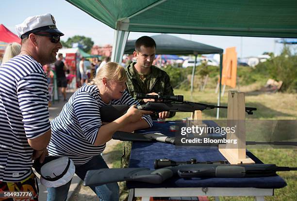 Soldier watches as a woman tries out a military rifle at a demonstration stand during Russian Navy day at the Vistula lagoon in Baltiysk, Russia, on...