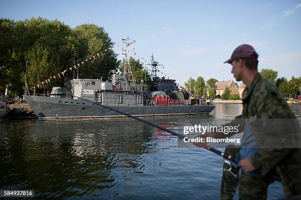 Man fishes near a Russian naval warship at its moorings during Russian Navy day at the Vistula lagoon in Baltiysk, Russia, on Sunday, July 31, 2016....