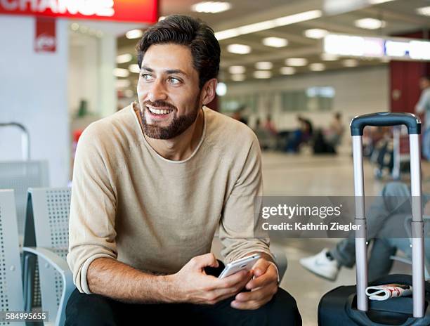 man at airport, mobile phone in hand - airport smartphone stock-fotos und bilder