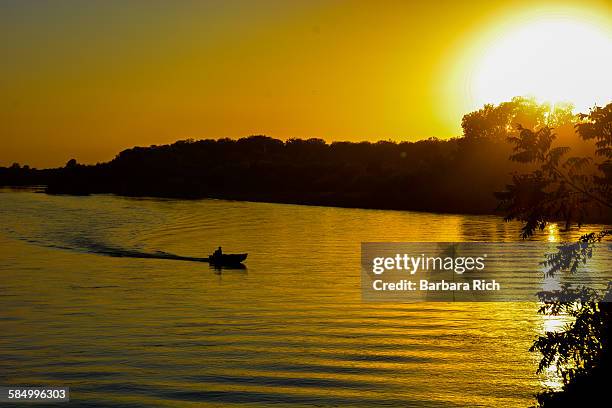 day's end on the river with boat silhouette - sunset barbara stock-fotos und bilder