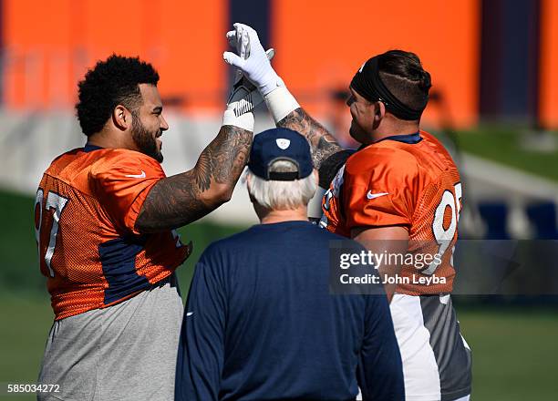 Denver Broncos defensive tackle Phillip Taylor and Denver Broncos defensive end Derek Wolfe high five on the field before practice during day 5 of...