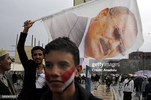 Man holds poster as people gather to support the "supreme council" which was established for state affairs by Houthi and former President Ali...