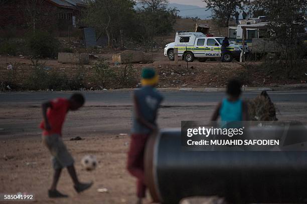 Children play as South African Police vehicle patrols the area on August 1, 2016 on the outskirts of Vuwani in the northern province of Limpopo. The...