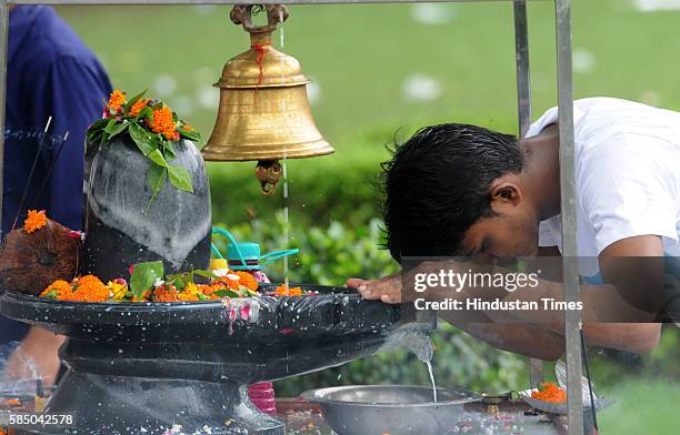 Devotees offer milk, honey, Gangajal, curd and coconut water on a Shivling, on the morning of Savan Shivratri festival at Shiv Murti Rangpuri on...