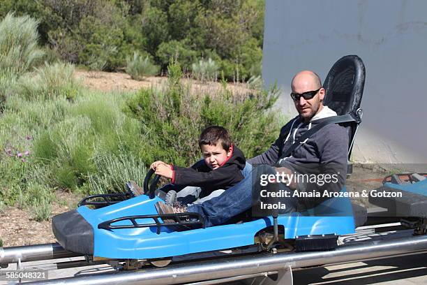 father and son on a rollercoasterer - famille montagnes russes photos et images de collection