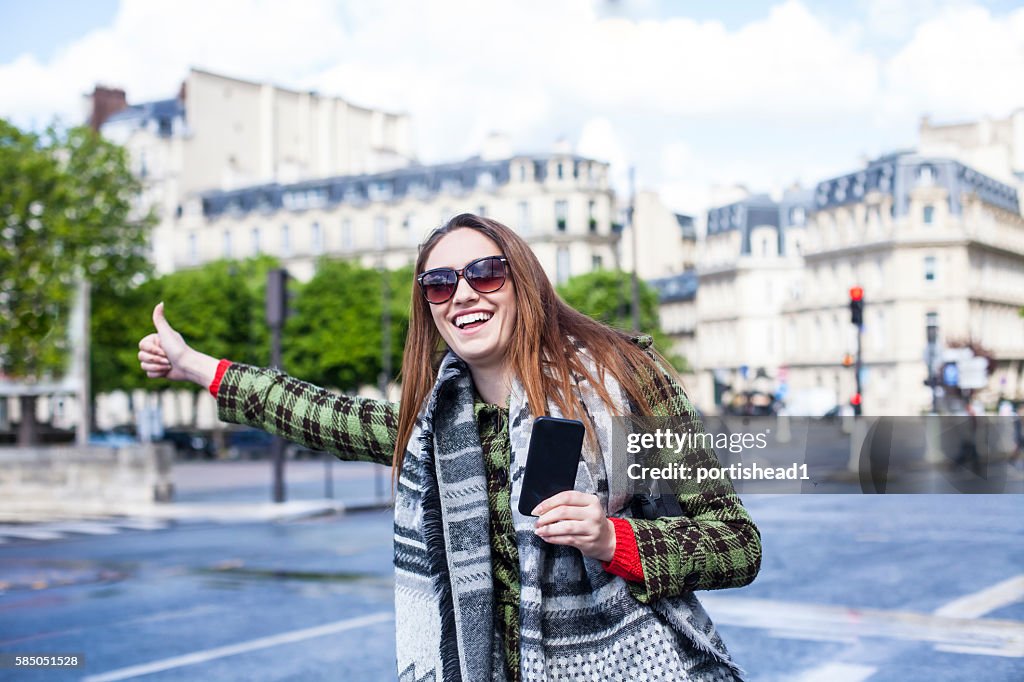 Jeune femme avec pouce levé pour l’autostop à Chapms Elysées