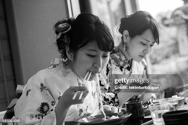 girls wearing traditional kimono costume eating noodle in kyoto japan - geisha eating stockfoto's en -beelden