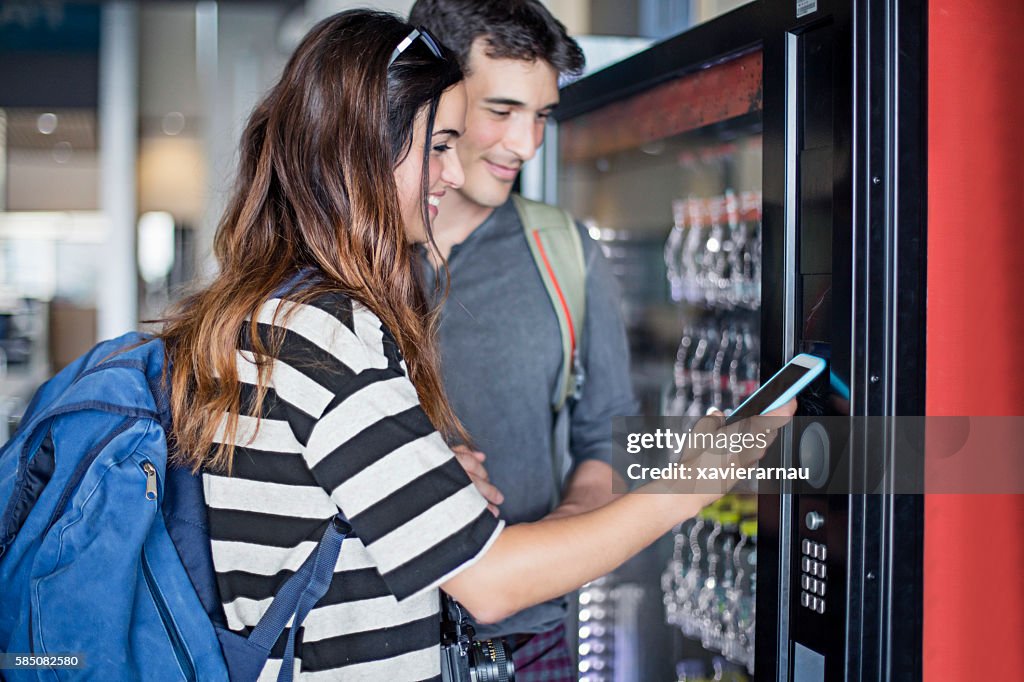 Young couple paying with mobile phone the soft drink