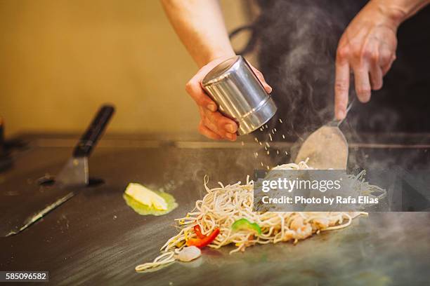 chef seasoning noodles on griddle - sales occupation fotografías e imágenes de stock