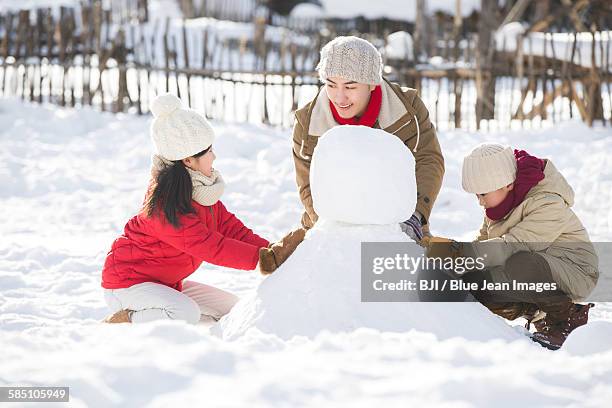 happy father and children making snowman together - chinese father and son snow stock pictures, royalty-free photos & images