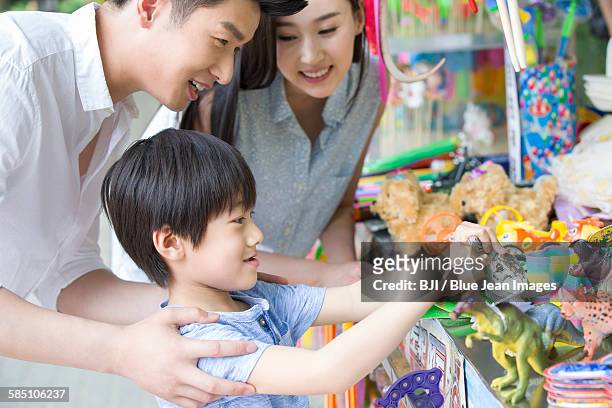 parents and son buying toys - woman picking up toys stock pictures, royalty-free photos & images