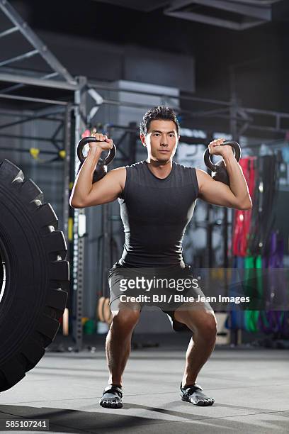 young man training with kettlebells in gym gym - musculation des biceps photos et images de collection