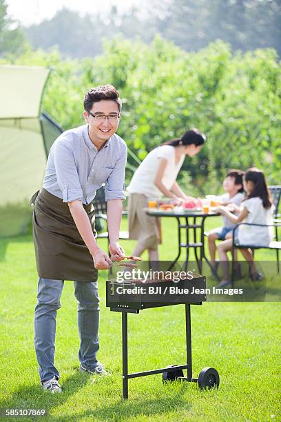 young family barbecuing outdoors - front view portrait of four children sitting on rock stock-fotos und bilder
